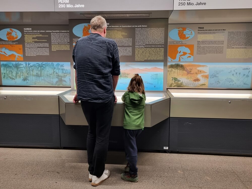 Vater und Kind betrachten eine Tafel zur Erdgeschichte (Perm) im Senckenberg Naturmuseum Frankfurt