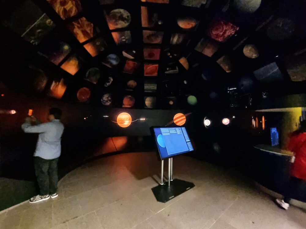 Dunkler Ausstellungsraum mit leuchtenden Planeten und interaktivem Terminal im Senckenberg Naturmuseum Frankfurt